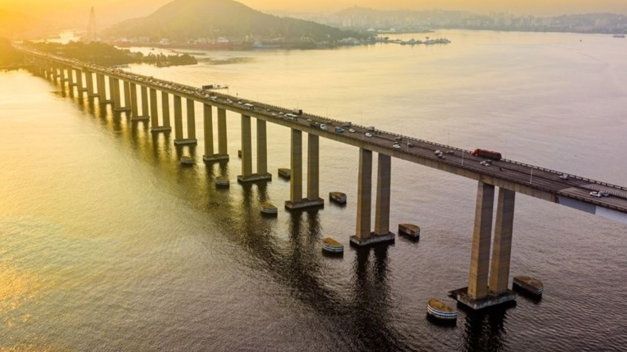 Vista aérea da Ponte Rio-Niterói com tráfego sobre a Baía de Guanabara ao pôr do sol.