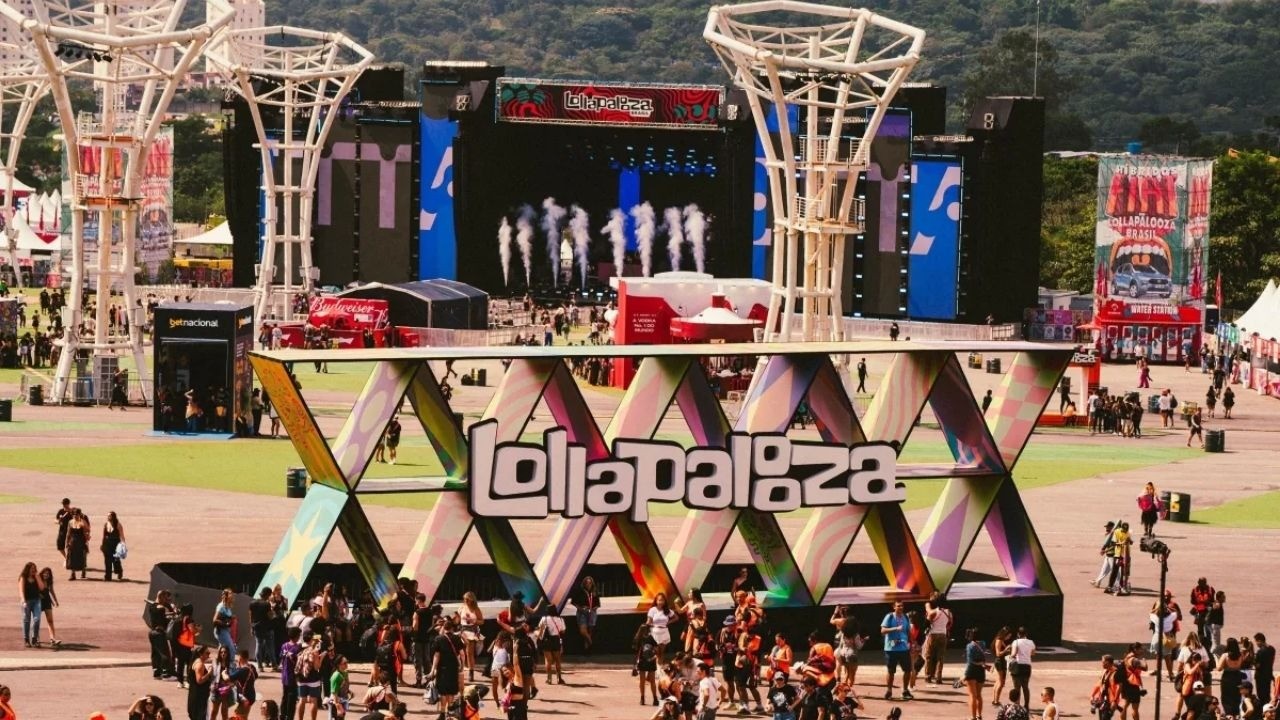 Festival Lollapalooza com grande sinal colorido "Lollapalooza", palco, torres, multidão e tendas.