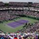 Vista panorâmica do estádio lotado do Miami Open, com quadra de tênis roxa e dois jogadores.