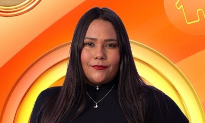 Retrato de Chaiany, mulher de cabelos escuros, blusa preta, colares e batom vermelho em fundo laranja.