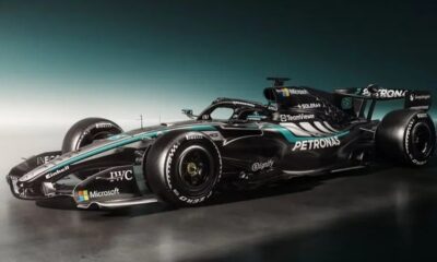 Carro de Fórmula 1 preto com detalhes em turquesa e diversos logos de patrocinadores.