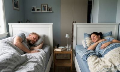 Homem e mulher dormem pacificamente em camas separadas, com uma mesa de cabeceira entre eles.