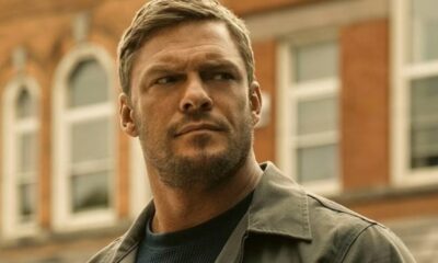 O ator Alan Ritchson, com expressão séria e barba por fazer, em imagem da série Reacher.