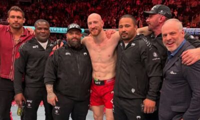 Joe Pyfer sem camisa celebra sorridente com sua equipe no octógono após a luta do UFC.
