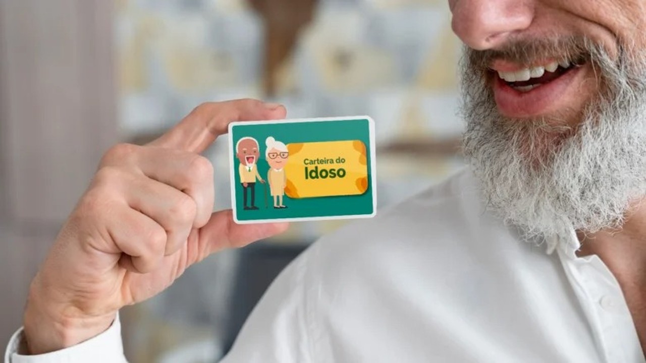 Homem sorrindo segurando a Carteira do Idoso, cartão verde com ilustrações de idosos.