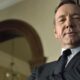Rosto de Kevin Spacey em close-up, vestindo terno e gravata, olhando diretamente.