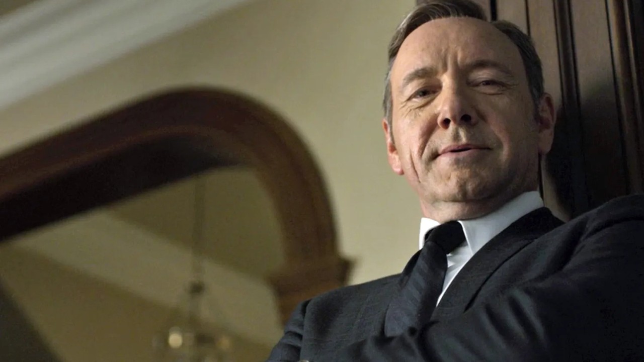 Rosto de Kevin Spacey em close-up, vestindo terno e gravata, olhando diretamente.