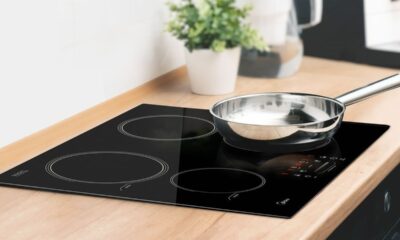 Cooktop de indução preto embutido em bancada de madeira com panela de metal brilhante.