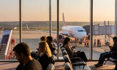 Pessoas esperam em saguão de aeroporto com avião da Gol e funcionários na pista.