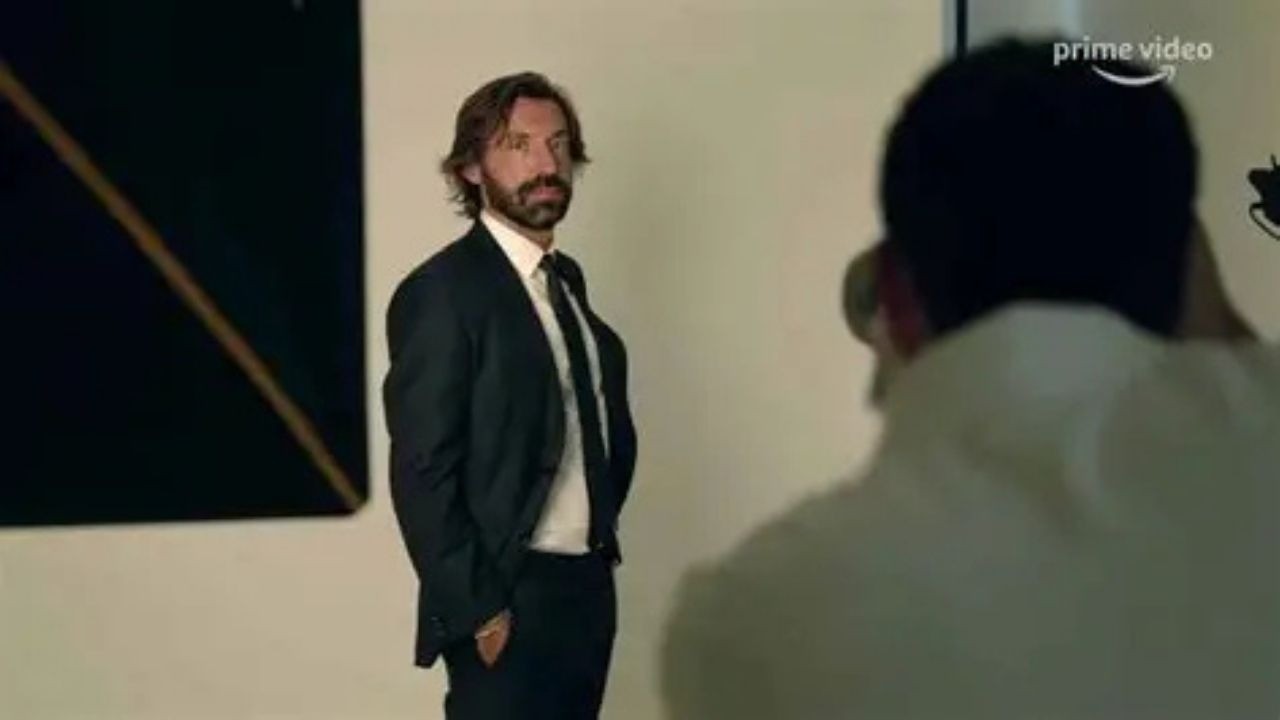 Andrea Pirlo, de terno, posa para fotógrafo, com logo Prime Video visível.