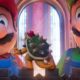 Mario e Luigi do filme, olhando à frente, com uma pequena figura de Bowser entre eles.