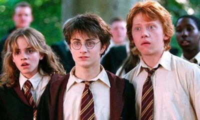Hermione, Harry e Ron em uniformes de Hogwarts com expressões de surpresa e olhos arregalados.