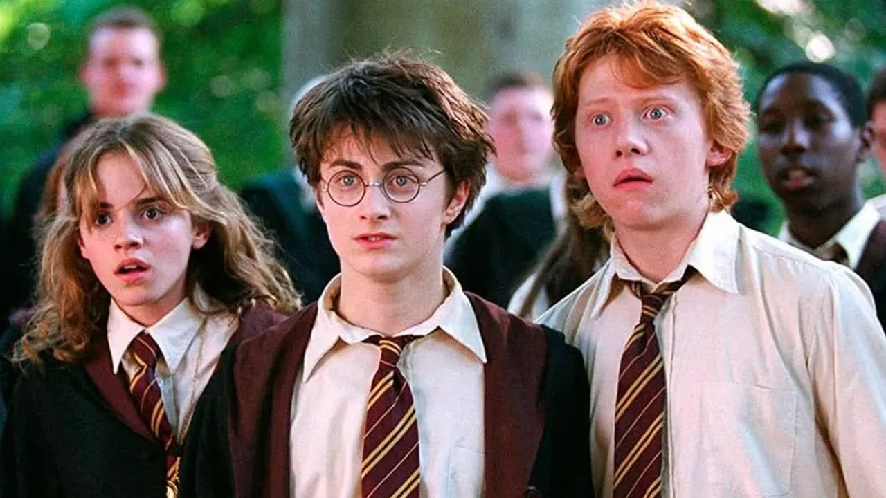 Hermione, Harry e Ron em uniformes de Hogwarts com expressões de surpresa e olhos arregalados.