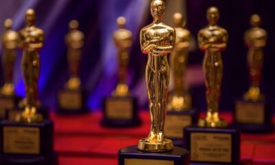 Várias estatuetas douradas do Oscar em exibição, uma em primeiro plano e outras desfocadas.