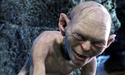 Close-up de Gollum, criatura pálida, com olhos azuis brilhantes e um sorriso ameaçador.