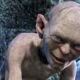Close-up de Gollum, criatura pálida, com olhos azuis brilhantes e um sorriso ameaçador.