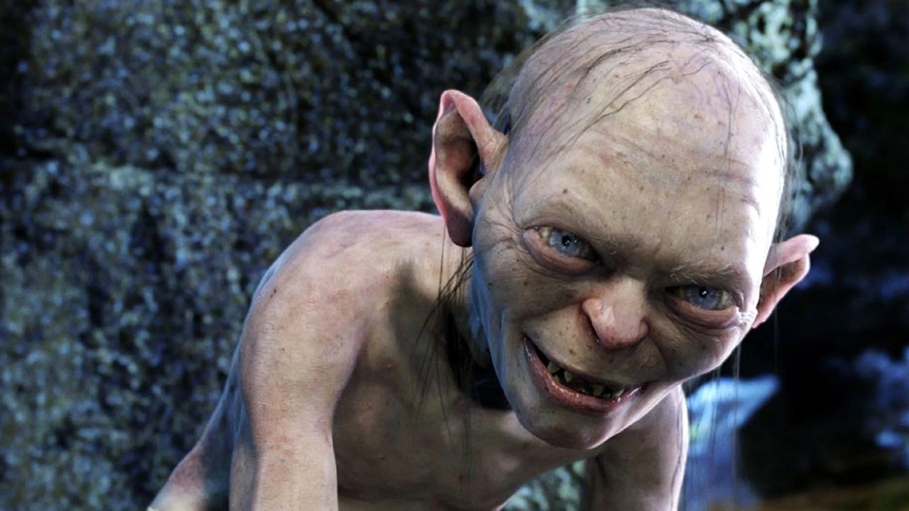 Close-up de Gollum, criatura pálida, com olhos azuis brilhantes e um sorriso ameaçador.