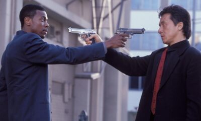 Jackie Chan e Martin Lawrence apontam armas um para o outro em confronto.