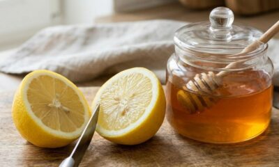 Duas metades de limão e um pote de mel com pegador em tábua de madeira.