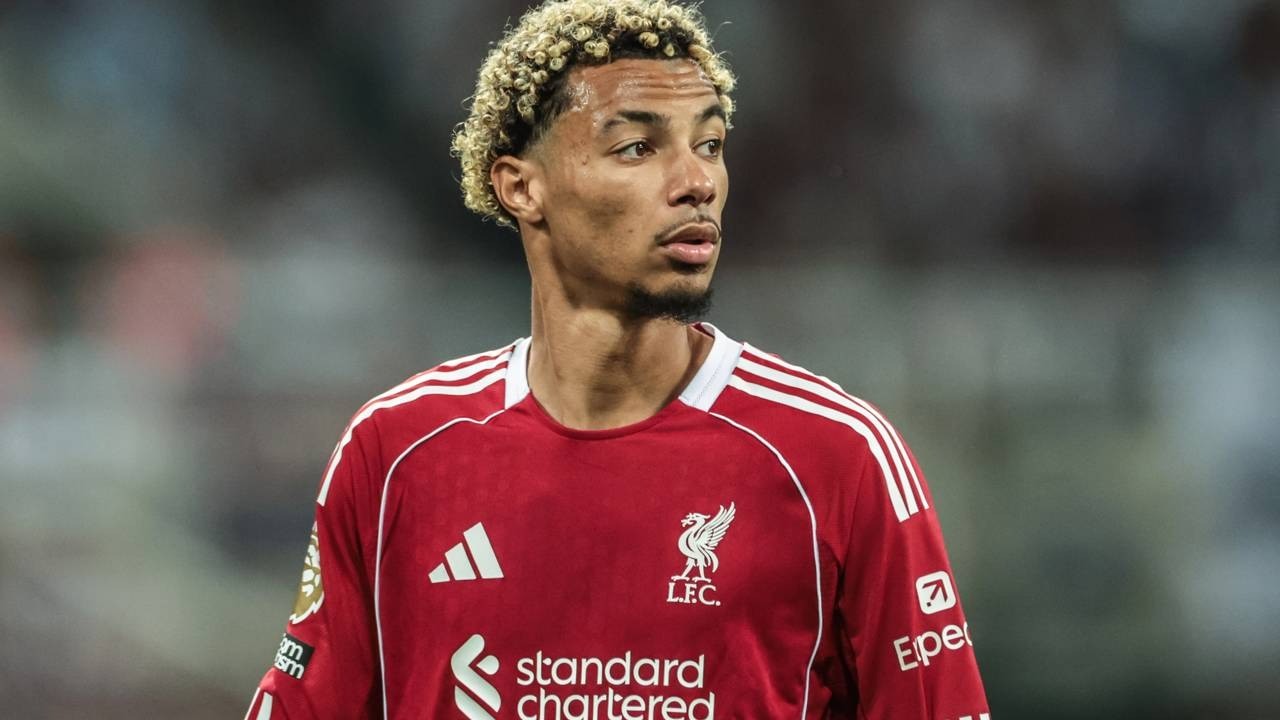 Hugo Ekitiké veste camisa vermelha do Liverpool com cabelo loiro encaracolado e barba.