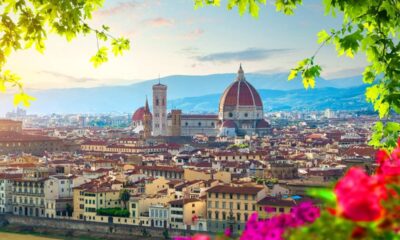 Vista panorâmica de Florença, com o Duomo e campanário, emoldurada por folhas e flores.