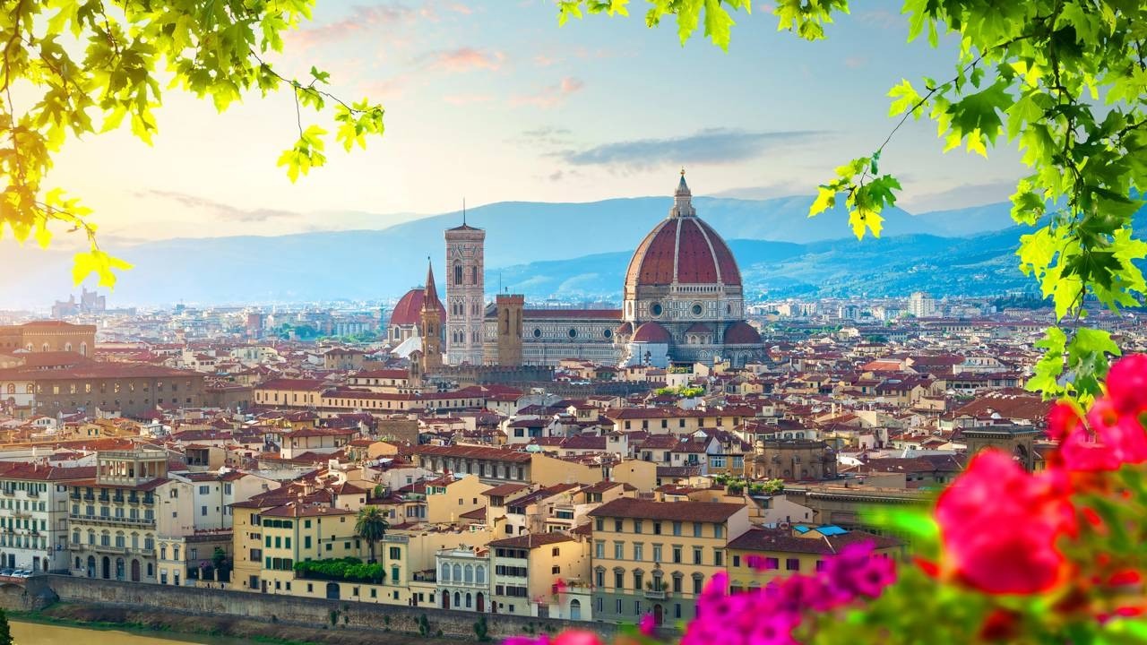 Vista panorâmica de Florença, com o Duomo e campanário, emoldurada por folhas e flores.