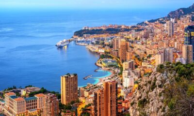 Vista aérea de Mônaco ao anoitecer, cidade costeira, edifícios, mar, navio e porto com iates.