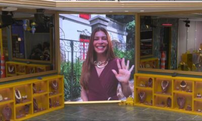 Grazi Massafera sorrindo e acenando em tela gigante, em cenário com joias e espelhos.