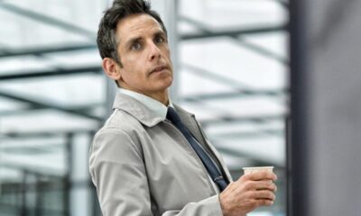 Homem, Ben Stiller, meio corpo, olhando pensativo para cima, segurando copo de papel branco.