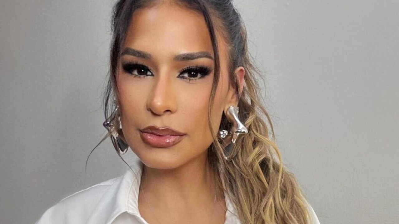 Rosto de Simone Mendes, maquiagem intensa nos olhos, lábios brilhantes, brincos prateados.