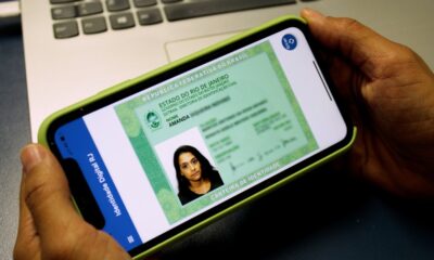 Pessoa segurando smartphone com a versão digital da Carteira de Identidade Nacional do Rio de Janeiro.