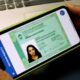 Pessoa segurando smartphone com a versão digital da Carteira de Identidade Nacional do Rio de Janeiro.