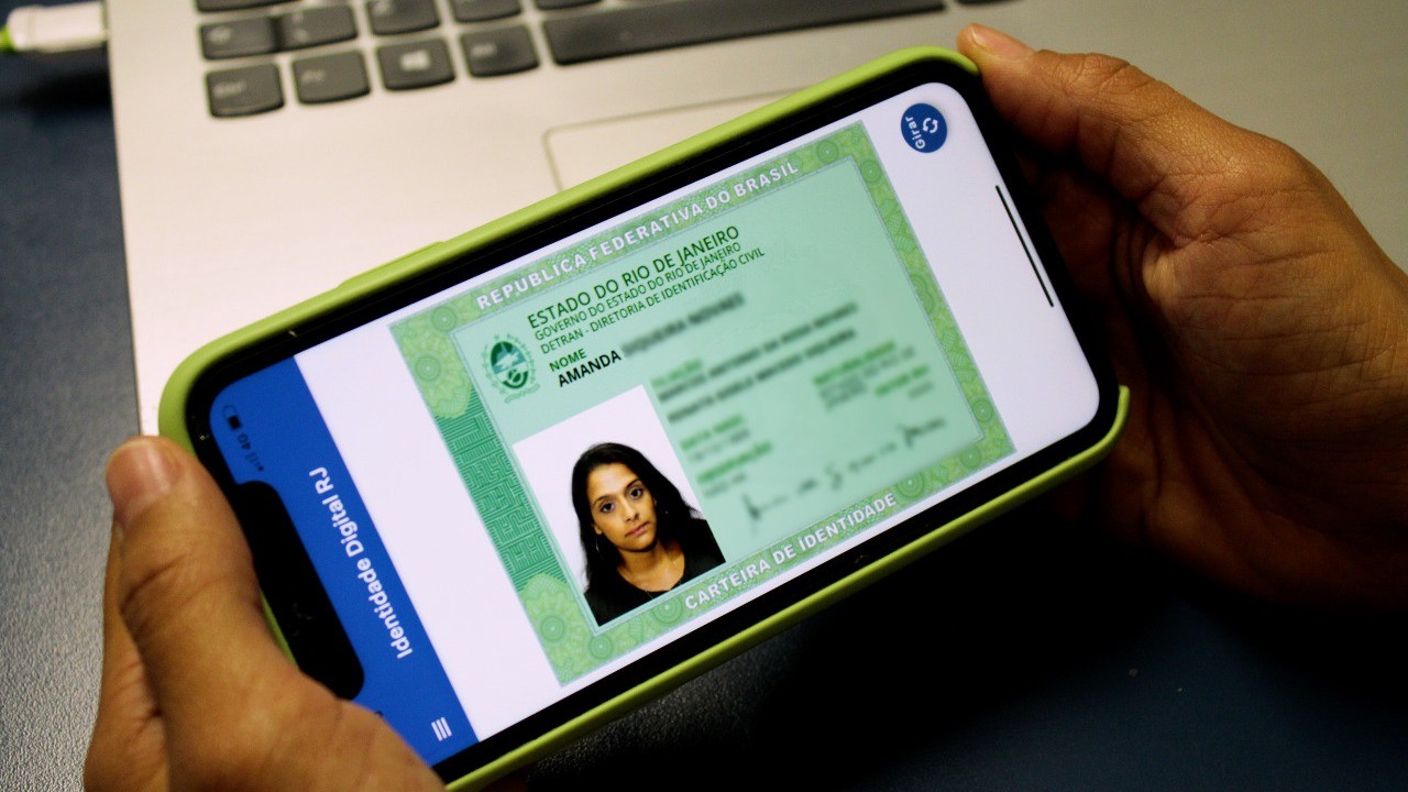 Pessoa segurando smartphone com a versão digital da Carteira de Identidade Nacional do Rio de Janeiro.
