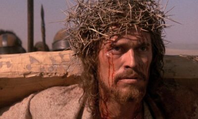 Homem barbudo com coroa de espinhos, rosto ensanguentado e expressão de dor.