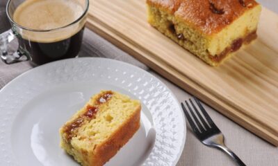 Fatia de bolo com recheio em prato branco, garfo, e xícara de café.