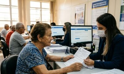 Idosa e atendente com máscara analisam documentos em centro de assistência para idosos.