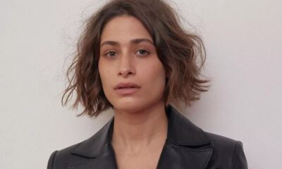Close-up de mulher com cabelo castanho curto, blazer preto e expressão séria, olhando para frente.