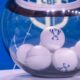 Globo de vidro transparente com bolas brancas exibindo logotipo de troféu azul, em fundo azul.