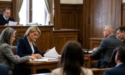 Um juiz e advogados em um tribunal, analisando documentos em mesa de madeira durante um processo.