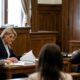 Um juiz e advogados em um tribunal, analisando documentos em mesa de madeira durante um processo.