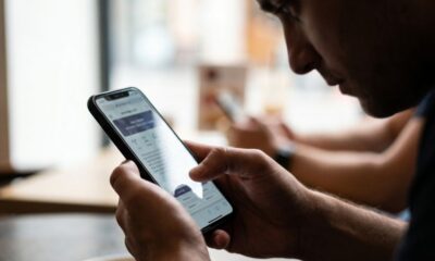 Homem segura smartphone com as duas mãos, navegando em tela que exibe símbolos astrológicos.