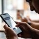Homem segura smartphone com as duas mãos, navegando em tela que exibe símbolos astrológicos.