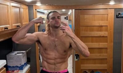 Noah Centineo sem camisa flexiona bíceps e abdômen em selfie no espelho de um trailer.