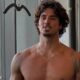 Gabriel Medina, sem camisa, cabelo e barba, falando, em academia com fundo urbano.
