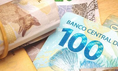 Cédulas de reais, com uma nota de R$100 'BANCO CENTRAL DO' e um maço amarrado.