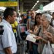 Mulher idosa tenta usar RioCard em validador de ônibus que exibe 'CARTÃO INVÁLIDO, BLOQUEADO'.