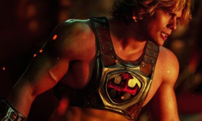 Nicholas Galitzine como He-Man, com armadura dourada, símbolo vermelho no peito e expressão determinada.