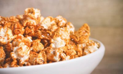 Close-up de pipoca doce caramelizada em tigela branca, com fundo desfocado.