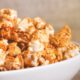 Close-up de pipoca doce caramelizada em tigela branca, com fundo desfocado.