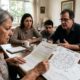 Família em mesa com documentos de inventário, mapa astral e calculadora, discutindo herança.